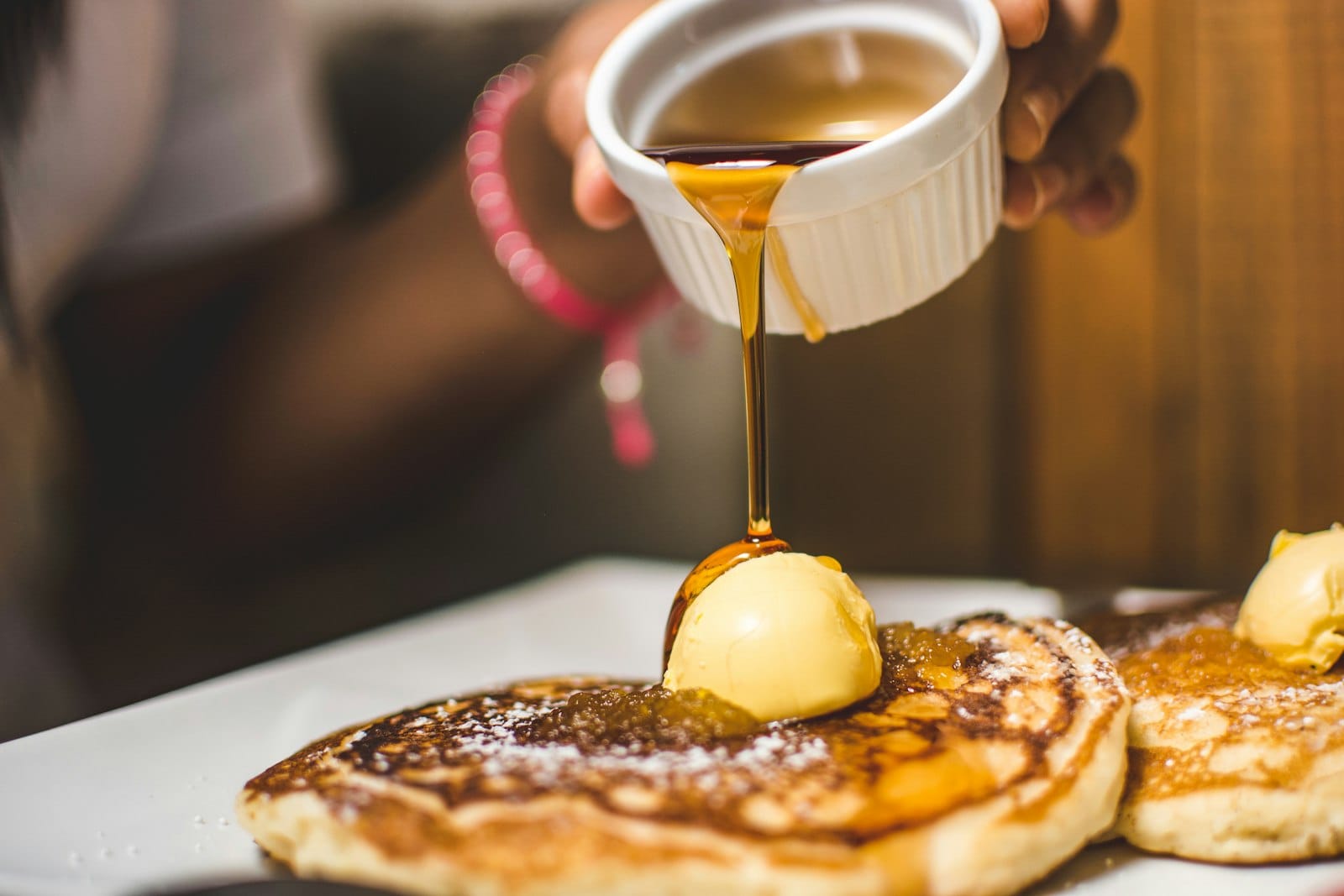 Maple syrup pouring over a stack of pancakes