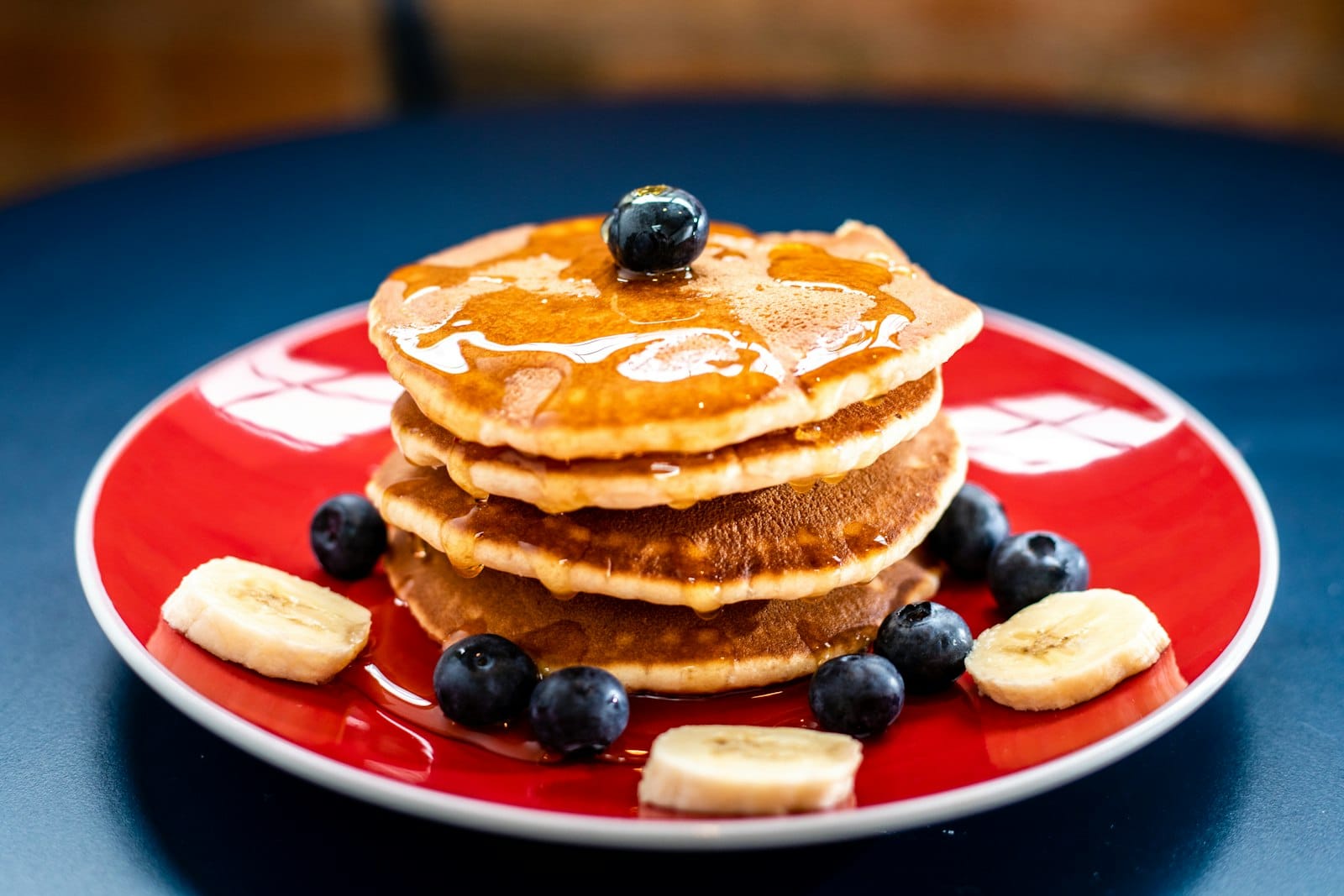 Stack of fluffy vegan pancakes with berries and maple syrup