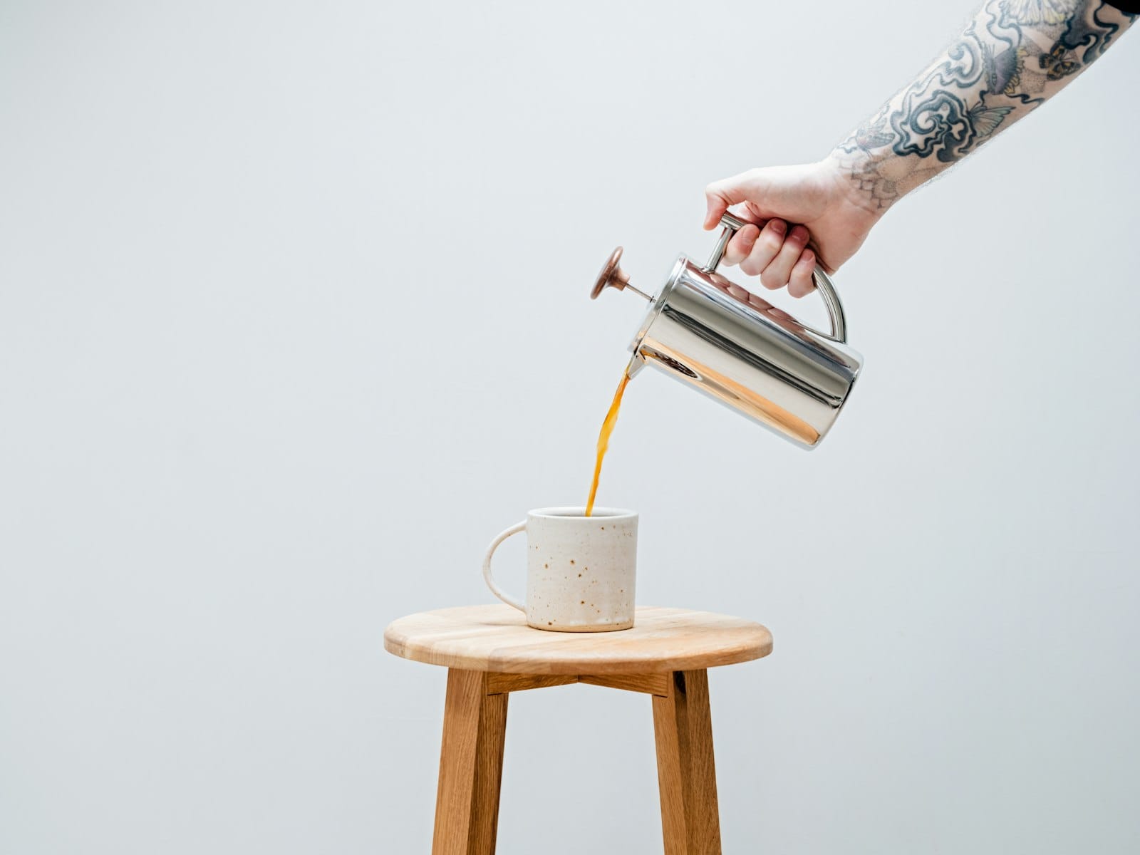 A jug of plant milk being poured into coffee