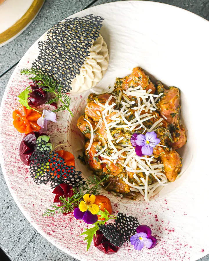An elegantly plated plant-based curry with cashew cream and edible flowers