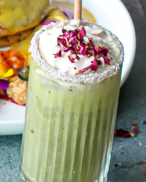 A fresh matcha cooler topped with coconut whip and dried rose petals