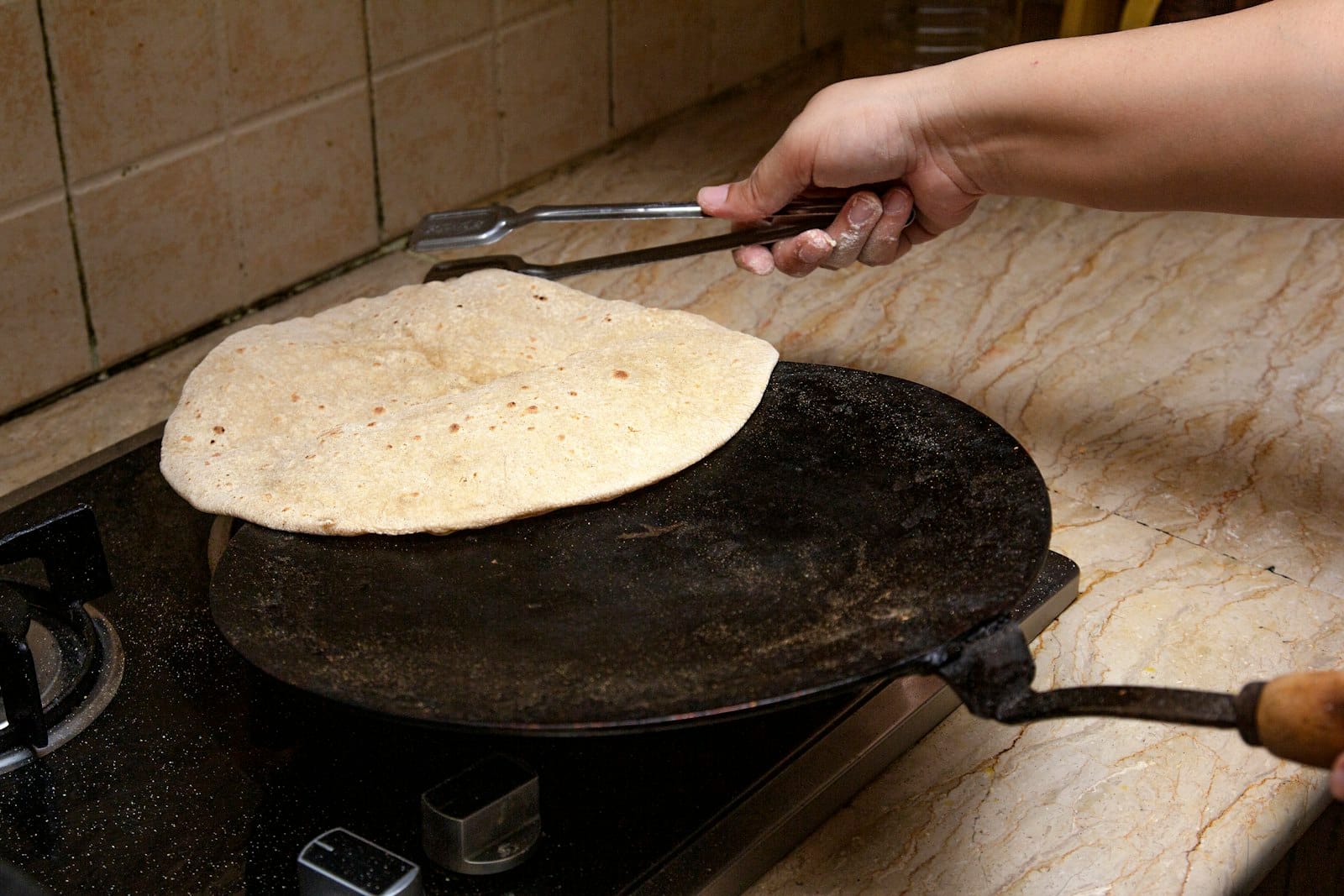 Hands cooking Indian food in a kitchen