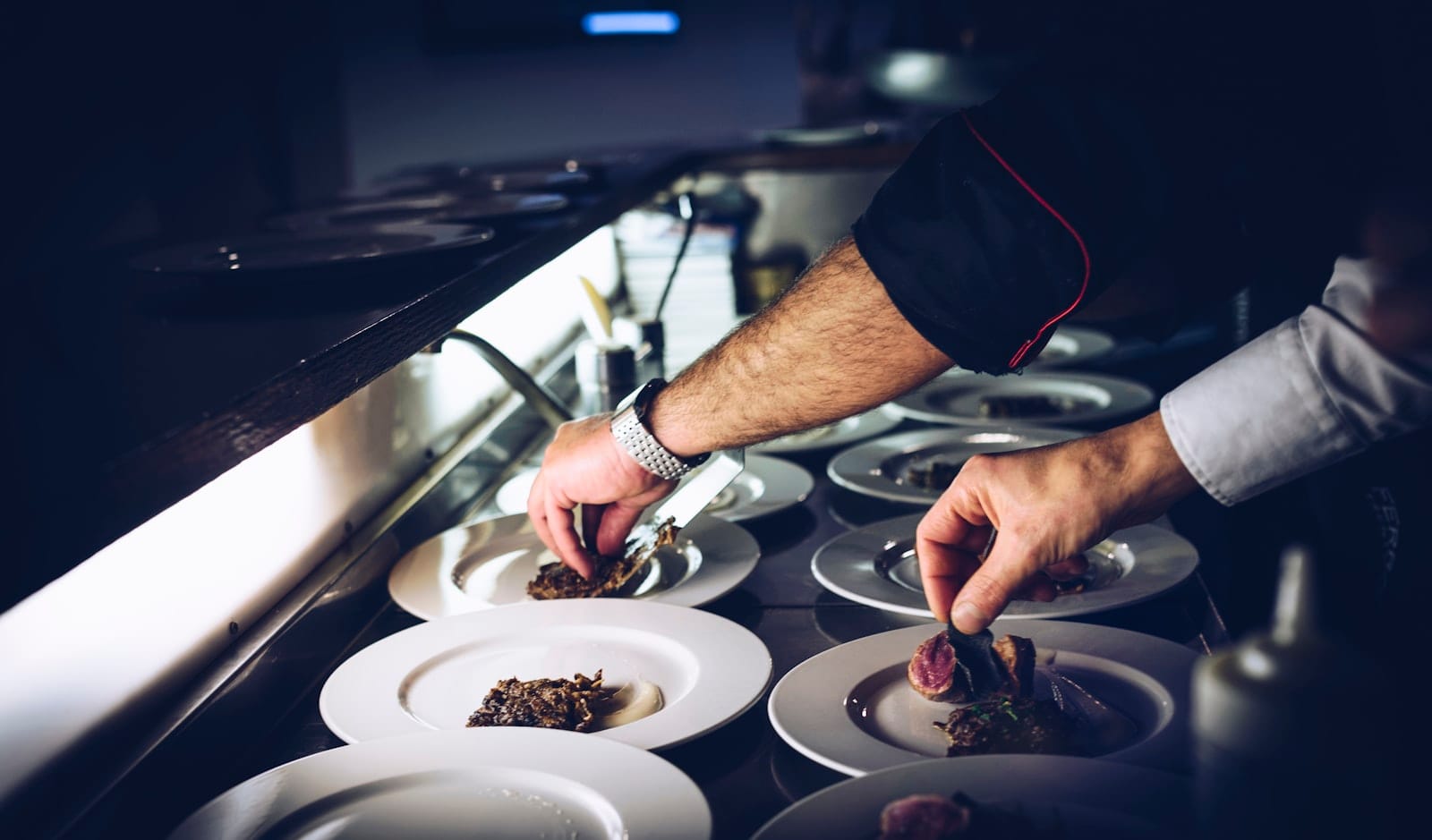 Hands plating food in a kitchen
